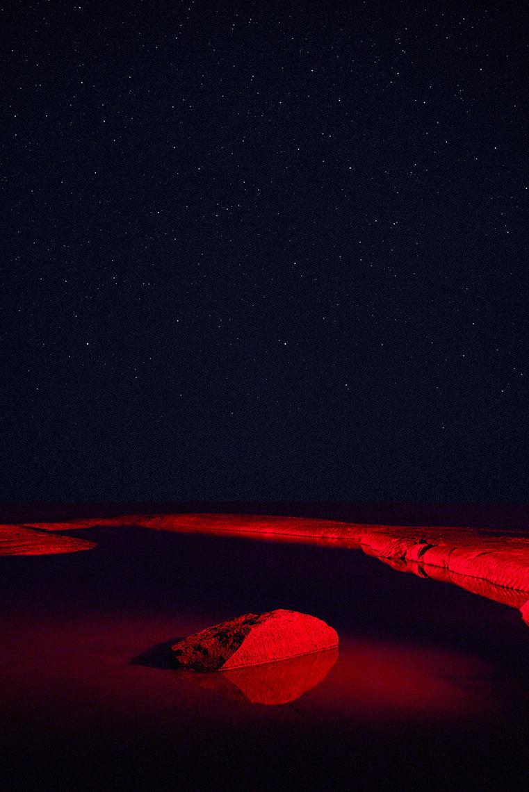 Red-lit rock formation under a dark sky