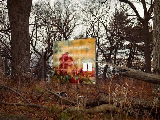Surreal landscape painting displayed in leafless forest.