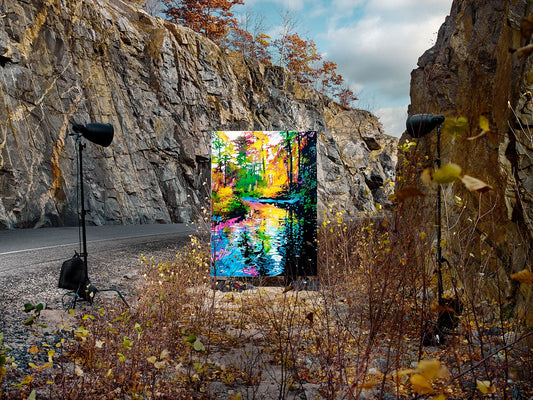 Bright forest painting lit between rocky cliffs near roadside.