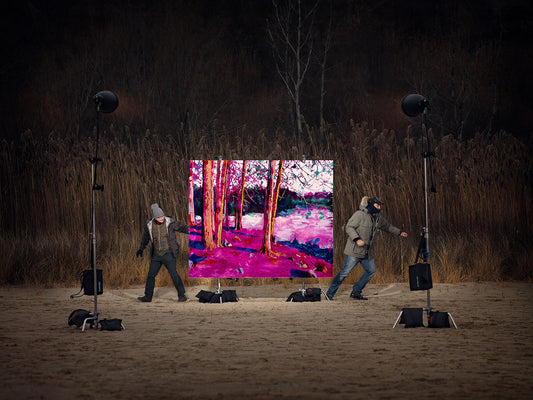Vibrant forest painting set up on sandy field at twilight.