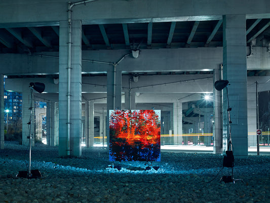 Vivid landscape painting lit beneath concrete overpass.